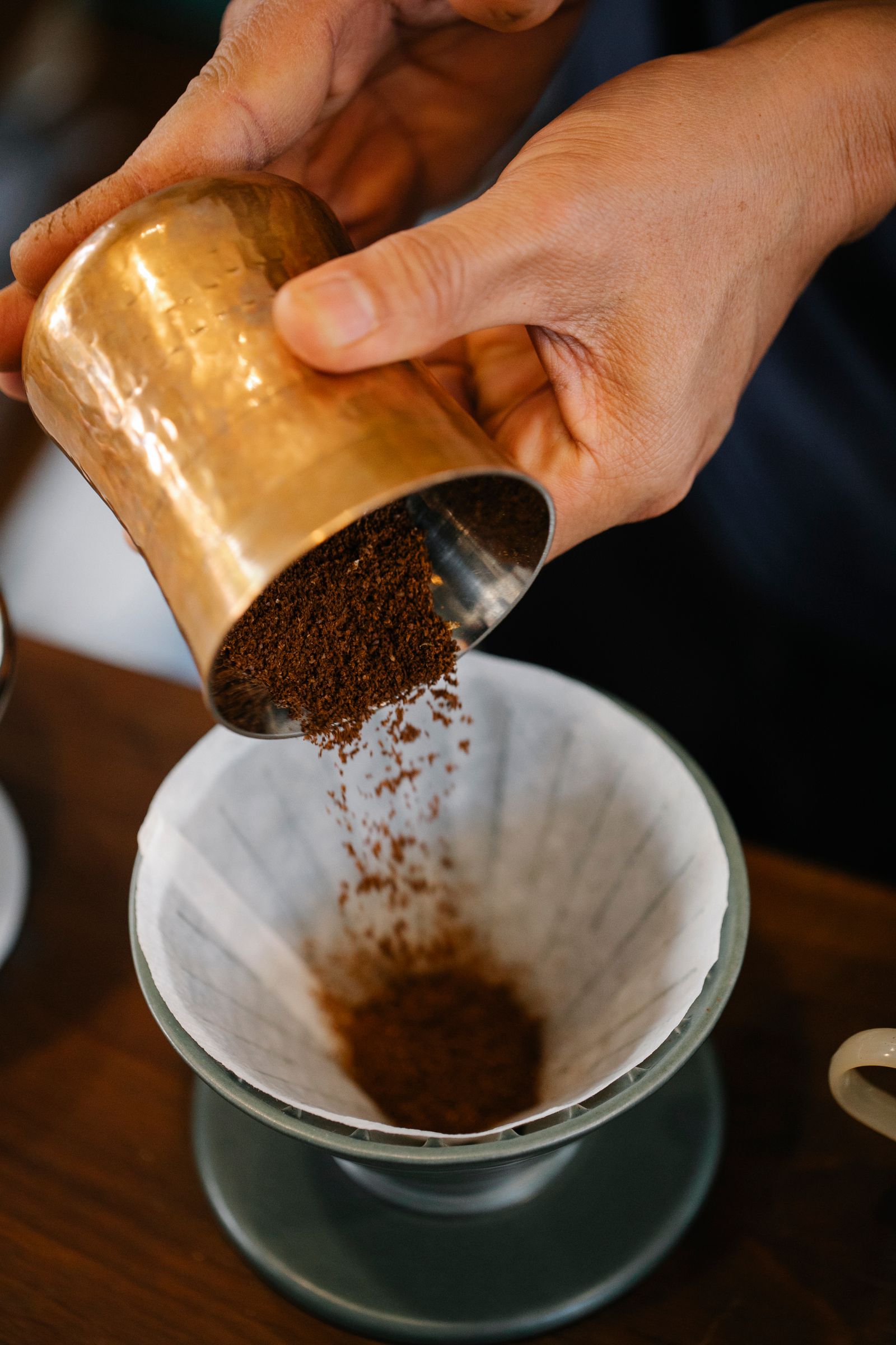 A barista pouring water into a flat-bottom coffee dripper