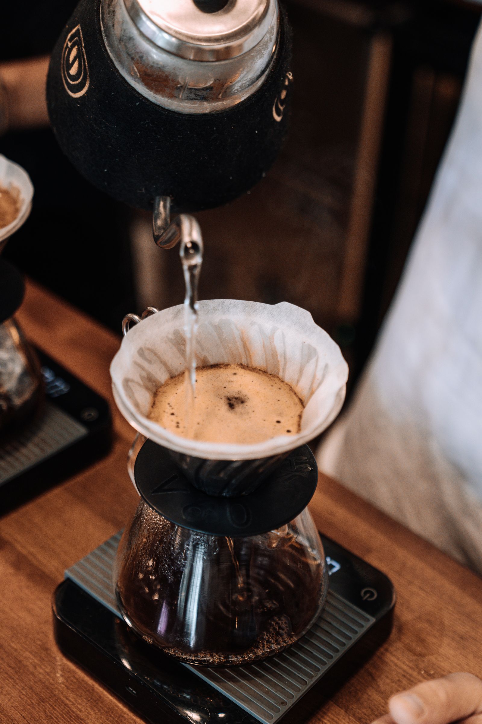 Pouring a thin, controlled stream of water over a pour over coffee dripper, Japanese café style