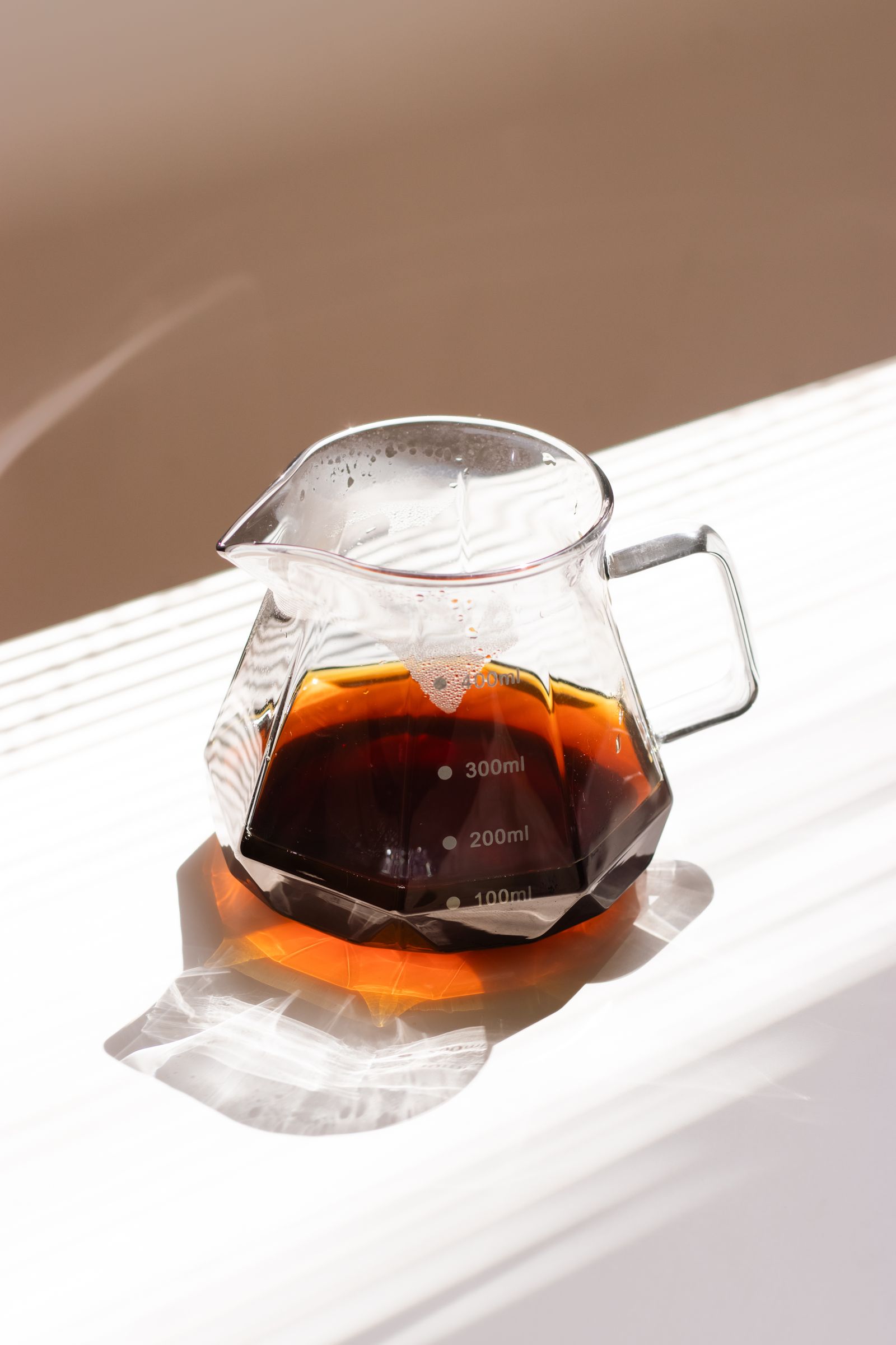 A glass server of clear, dark Kyoto-style cold brew coffee in morning light