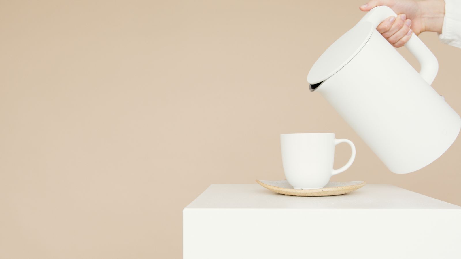 A person pouring a thin stream of water from a gooseneck kettle