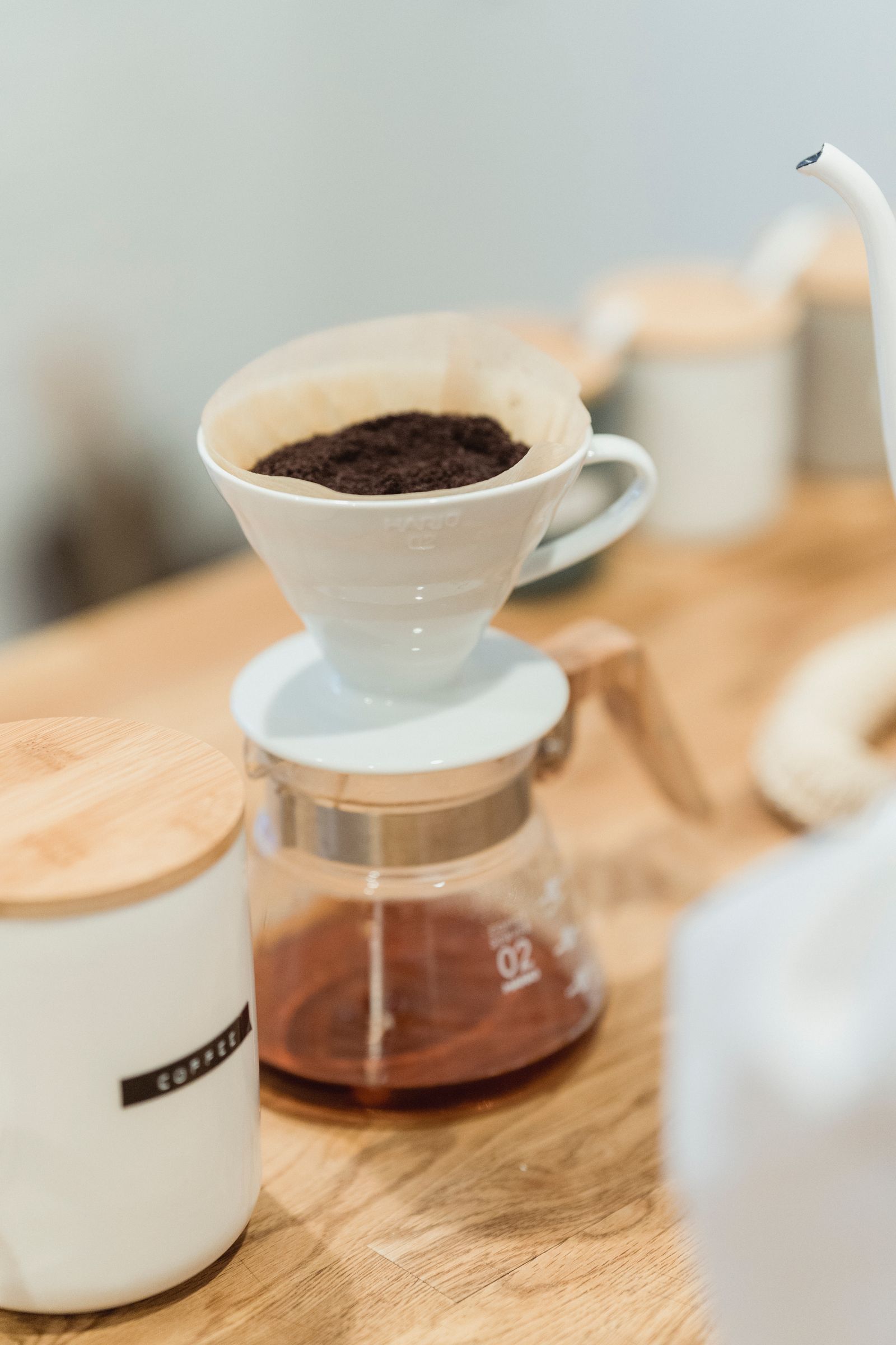 A ceramic cone coffee dripper with a paper filter set on a coffee pot